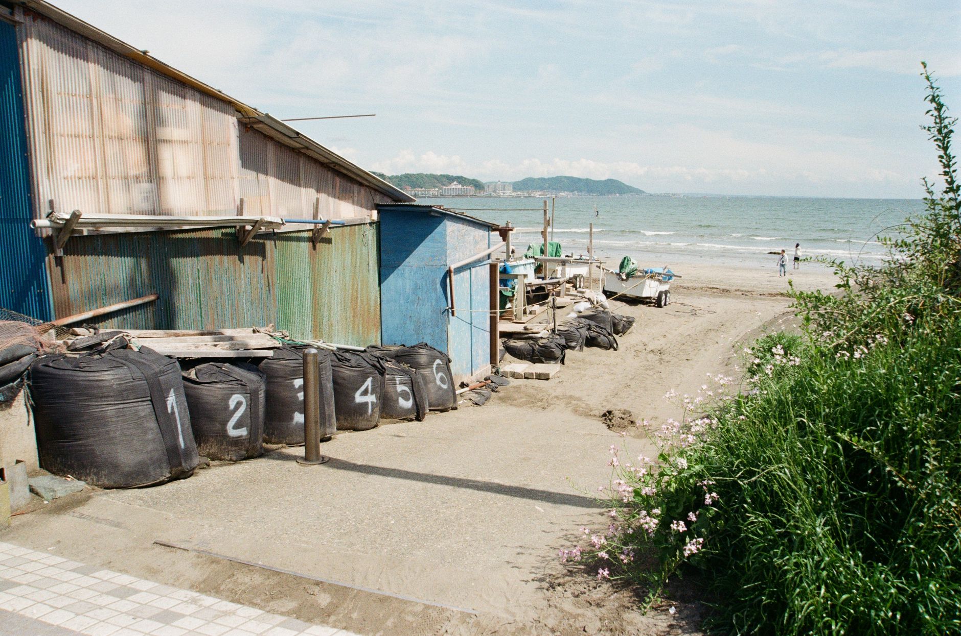 Rustykalna wiata i ponumerowane worki na plaży w Kamakurze
